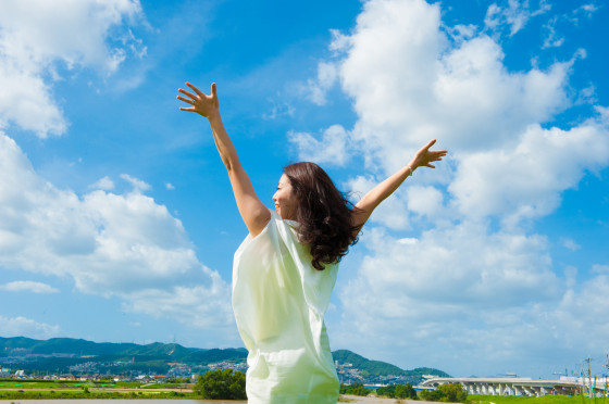 青空に向かって手を広げる一人の女性